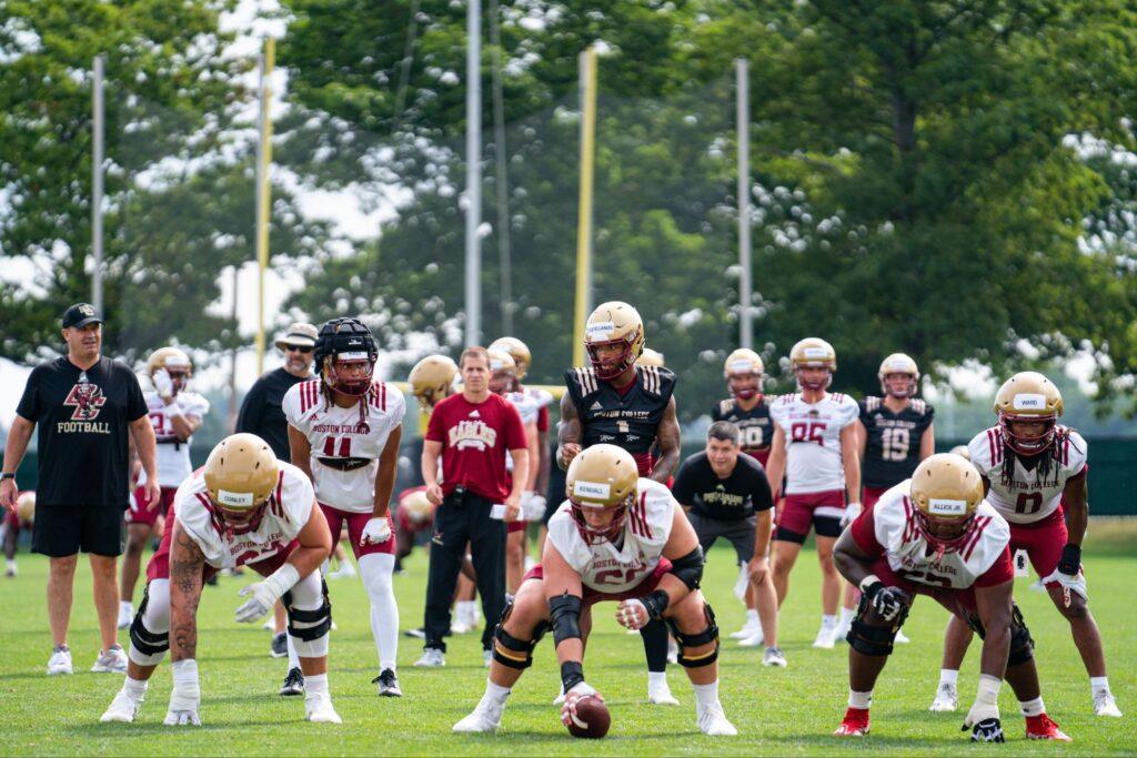 Football players in practice uniforms set up on a grassy field