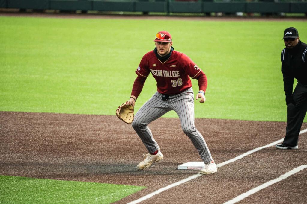 Baseball player in red uniform positioned at first base with a glove