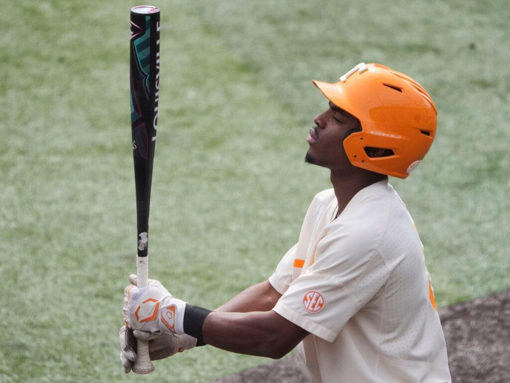 Player in orange helmet holding a bat in a baseball field setting