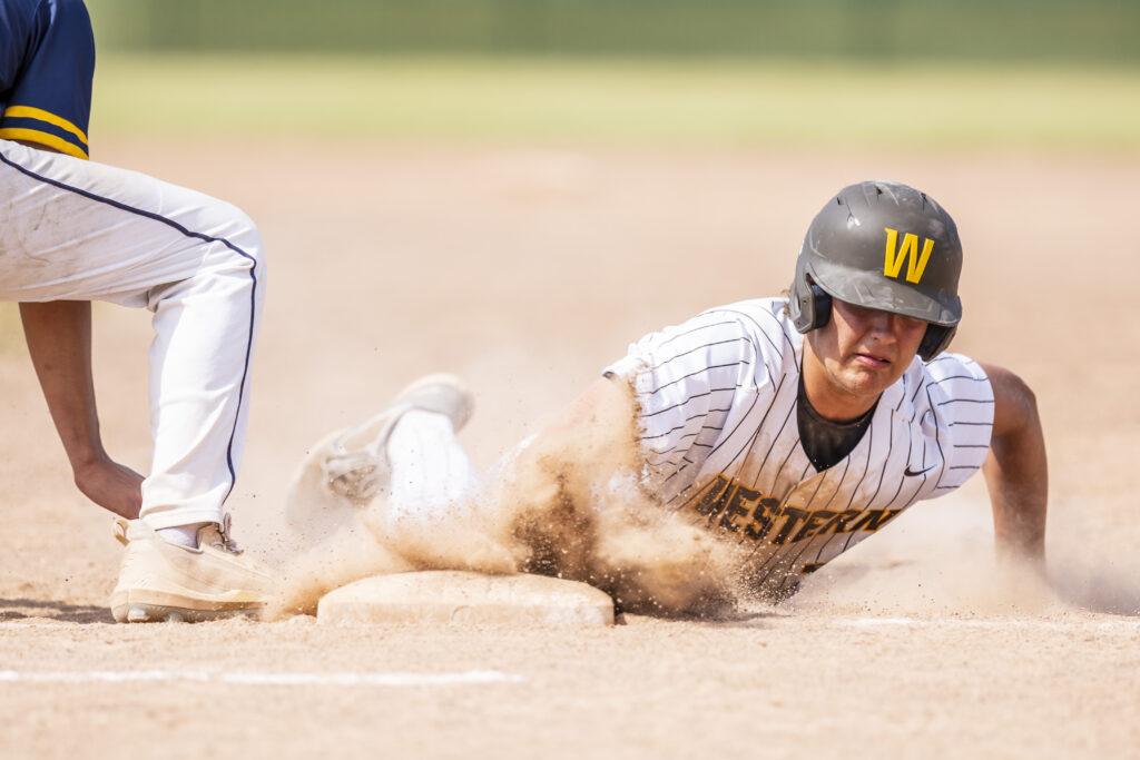 Player in a striped uniform sliding into a base, dirt flying