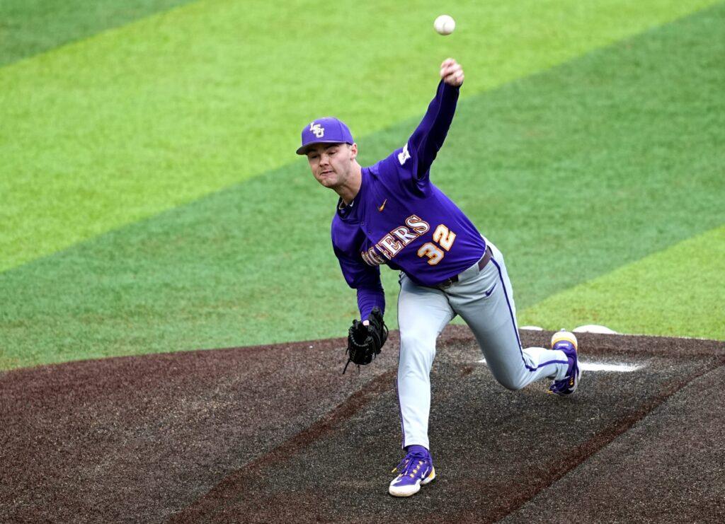 Baseball pitcher wearing purple and gray uniform throwing a baseball