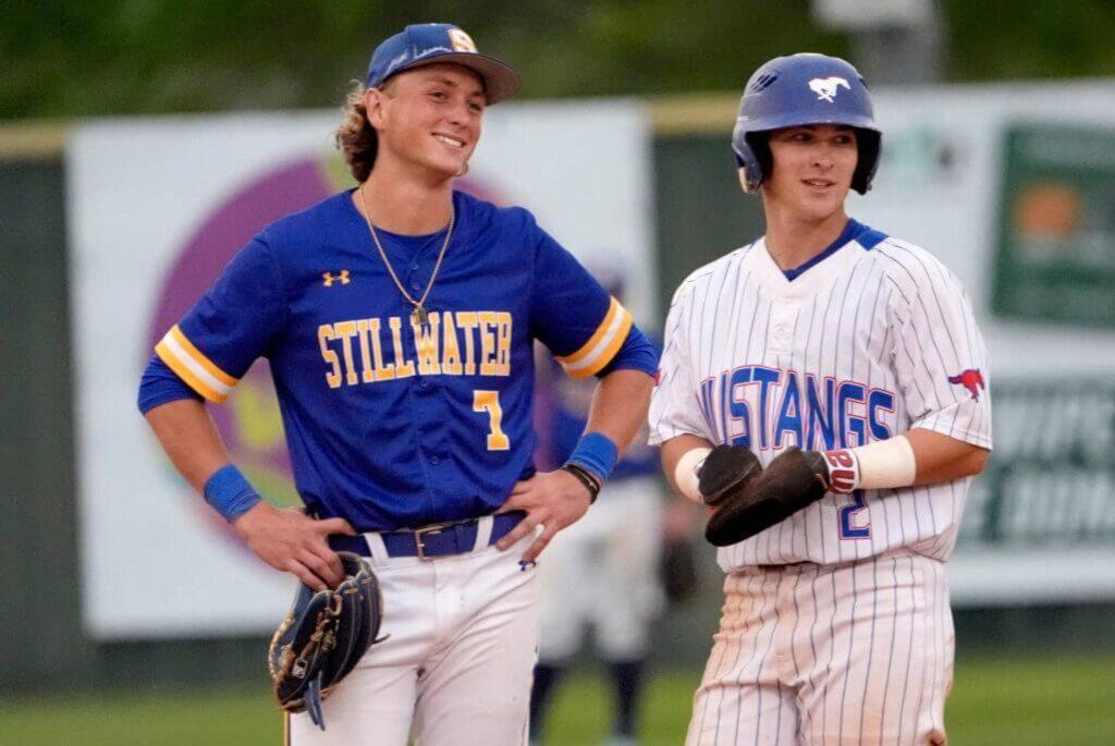 Two baseball players chatting on the field wearing uniforms