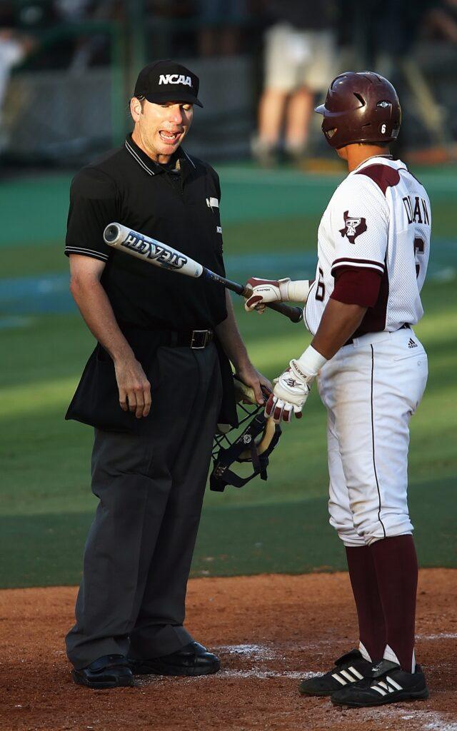 Umpire holding a helmet while player presents a bat
