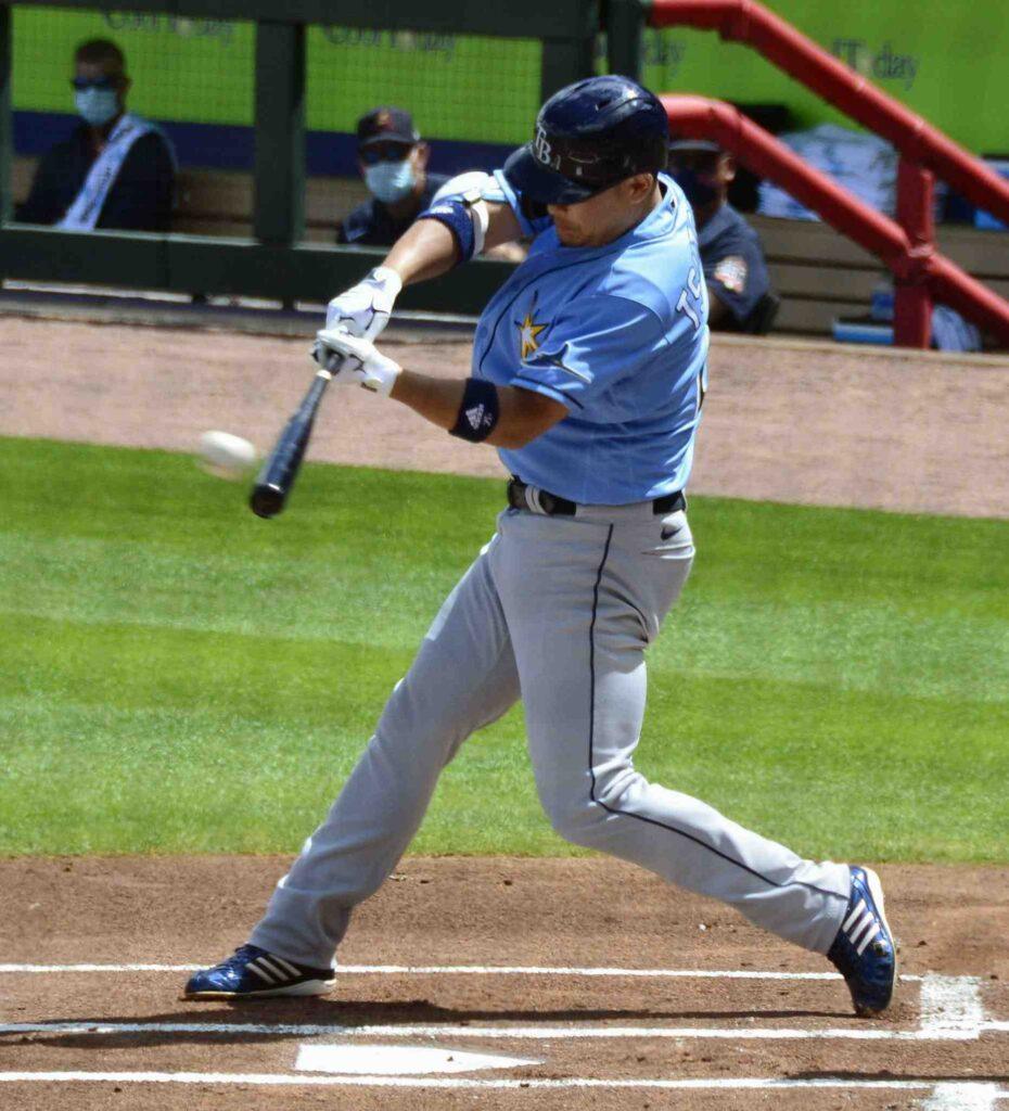 Baseball player in light blue uniform swinging a bat at a baseball