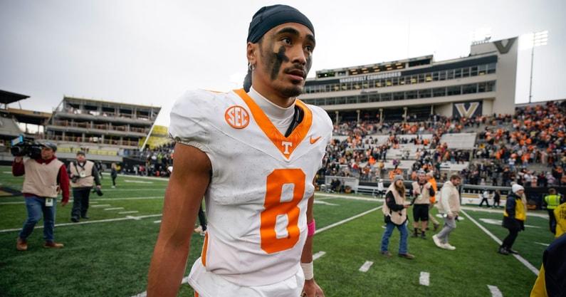 Football player in white and orange uniform walking on the field
