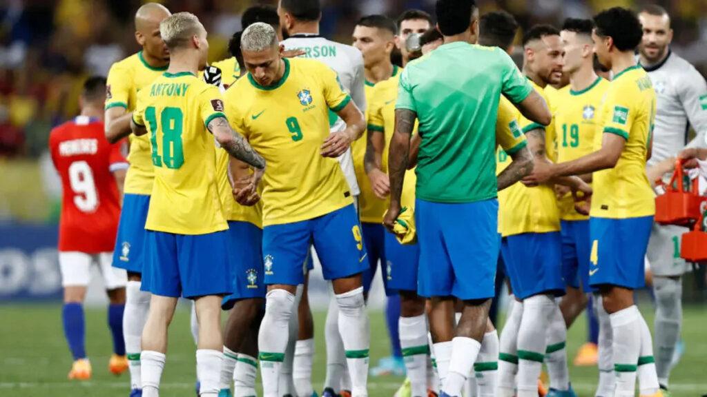 Brazil national soccer team in yellow jerseys huddled together on the field