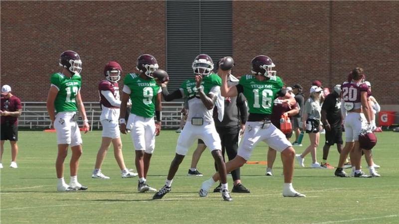 Five football players in practice uniforms on a grassy field